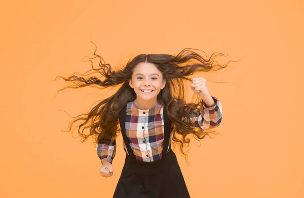 Air in her hair. natural beauty. Child with natural beautiful healthy hair yellow background. Tips for healthy hair. Girl kid long hair flying in air. Hairdresser salon. Beauty procedure. Extra light.