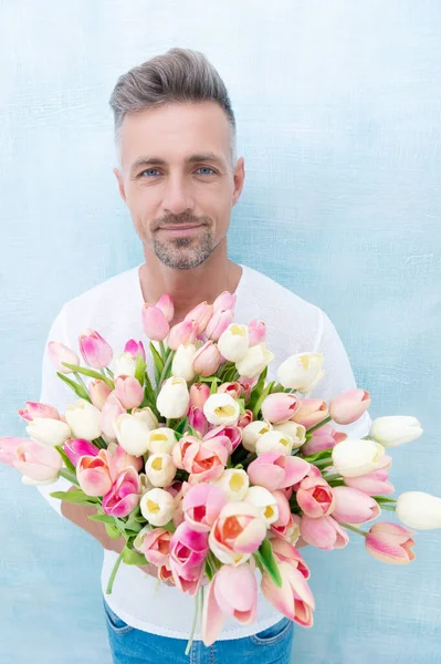 man with valentines day bouquet, selective focus. man with valentines day bouquet isolated on blue background. photo of man with valentines day bouquet for holiday. man with valentines day bouquet.