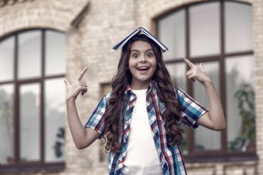 Küçük mutlu çocuk okul kitabını işaret ediyor. Açık havada, bilgi dolu..