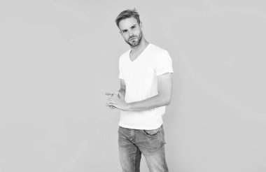 Saç ve sakal bakımı. Kendine güvenen ve yakışıklı, tıraşsız adam. Erkek modası. Erkek güzelliği. Beyaz gömlekli kıllı adam. Sarı arka planda sakallı genç adam..