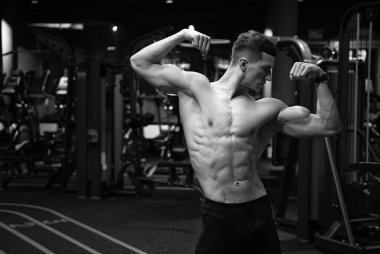 Sağlam gövdeli güçlü bir adam kol kasları kaslı spor salonunda çift kol pozisyonu almış, güçlü..