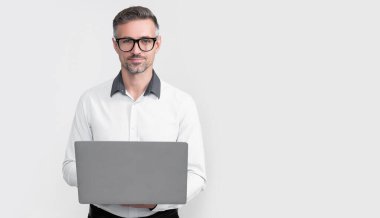 Gri arka planda bilgisayar üzerinde çalışan gözlüklü olgun bir serbest yazar..