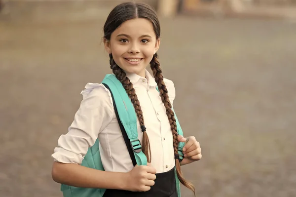 happy braided girl with backpack in school uniform.