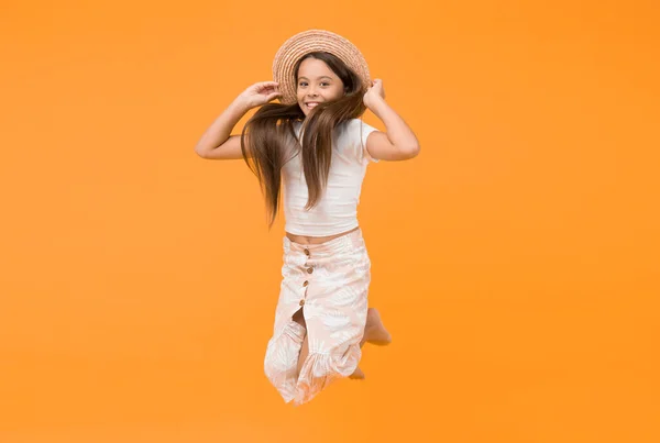 Lets have fun. party fun. carefree and happy kid jumping. summer beach fashion. childhood happiness. small girl wear straw hat. cheerful child on yellow background. holiday and vacation. free time.