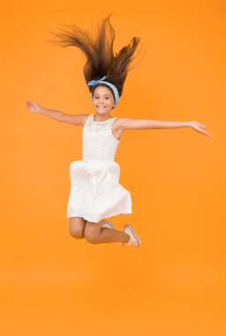 Havada zıplıyor. Hafifçe ve yavaşça. Özgürlük için. Enerji dolu bir çocuk uzun ve sağlıklı saçların tadını çıkarıyor. Güzel saç stili. Mutlu bir çocukluk. Tasasız bebek. Güzel saç stili. Kızlar için günlük saç stili.