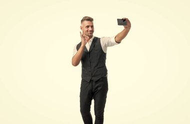 Takım elbiseli mutlu profesyonel adam beyaz üzerine izole edilmiş akıllı telefonlu video kaset hazırlıyor..