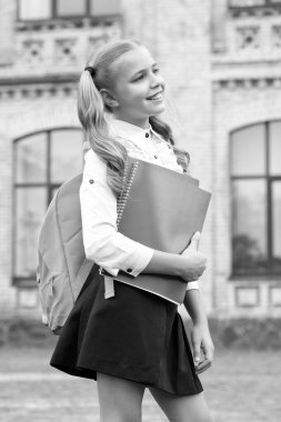 Okul üniformalı mutlu çocuk kitap ve sırt çantası taşıyor, bilgi günü..