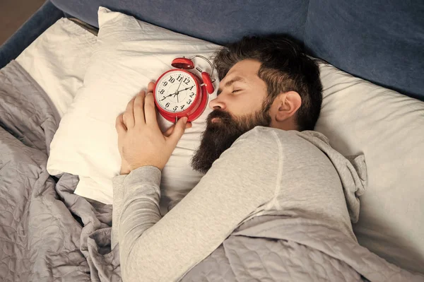 Man sleeping with alarm clock in bed, sleep time.