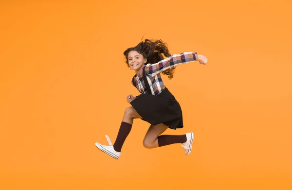Fun and jump. Happy childrens day. Jump concept. Break into. Feel inner energy. Girl with long hair jumping on yellow background. Carefree kid summer holiday. Time for fun. Active girl feel freedom.