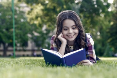 Başarılı olmak için okumalısın. Mutlu çocuk yeşil çimlerin üzerinde uzanan kitabı okuyor. Okul kütüphanesi. Edebiyat eğitimi. Ev ödevi. Edebiyat dersi. Yabancı dil öğreniyorum. İngilizce okulu. Zaman harcamaya değer..
