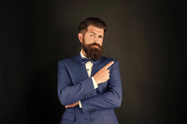 serious man in tuxedo bow tie. man in formalwear point finger on black background. male formal fashion. copy space.