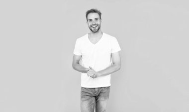 Sarı arka planda sakallı mutlu genç bir adam. Saç ve sakal bakımı. Kendine güvenen ve yakışıklı, tıraşsız adam. Erkek modası. Erkek güzelliği. Beyaz gömlekli kıllı adam..