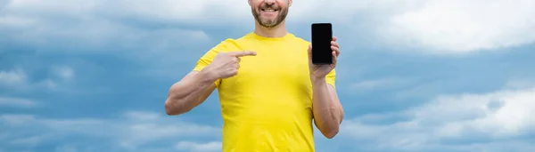 cropped view of man presenting screen of smartphone with copy space. pointing finger.