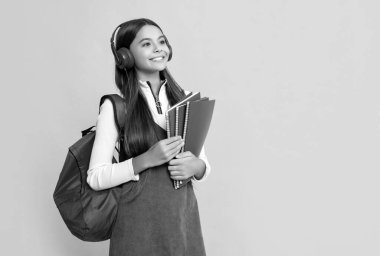 Okul çantalı, kulaklıklı, sarı arka planlı mutlu çocuk..