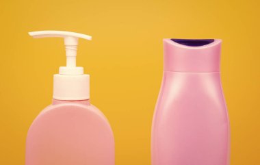 Duş, banyo, kozmetik ve tuvalet ürünleri için kapaklı plastik kaplar. Arka planda sarı fotokopi alanı, şişeler.