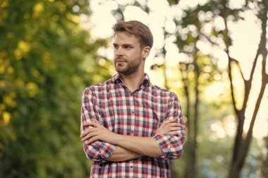 Çapraz elleri açık havada, kareli gömlekli genç adam..