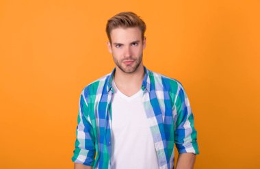 Gerçekten yakışıklı. Normal erkek portresi. Yakışıklı, sarı arka plan. İşaretli gömlekli genç adam. Ciddi bir erkek..