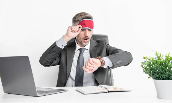 tired businessman check time in sleep mask at workplace.