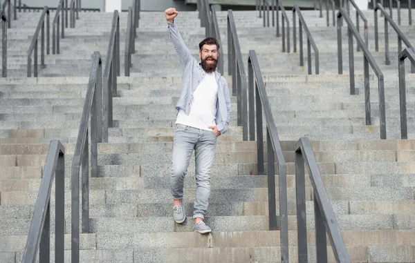 happy bearded guy walk downstairs. full length of guy with beard. hipster guy outdoor at stairs.