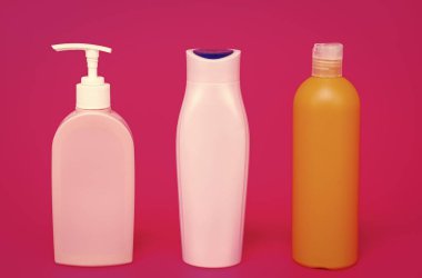 Sıvı kozmetik ürünleri için plastik kapları sıra pembe arka plan kopyalama alanı, şişeler.