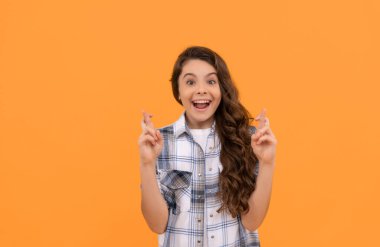 Sarı arka planda kareli gömlekli hayret dolu bir çocuk..