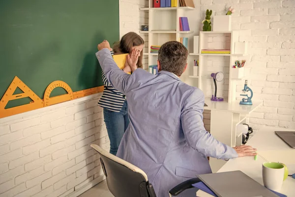 angry teacher shouting at child at blackboard.