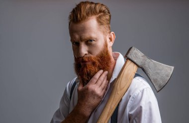 unshaven masculine man with axe isolated on grey. masculine man with axe in studio. masculine man with axe on background. photo of masculine man with axe.