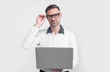 Gri arka planda bilgisayar üzerinde çalışan gözlüklü olgun bir iş adamı..