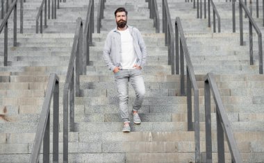 Sakallı adam aşağıda yürüyor. Sakallı bir adam. Merdivenlerde hippi bir adam var..