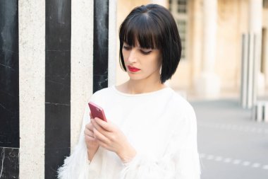 busy woman messaging on phone outdoor. woman messaging on phone outside. woman messaging on phone in the street. woman messaging on phone.
