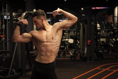 Sağlam gövdeli güçlü bir adam kol kasları kaslı spor salonunda çift kol pozisyonu almış, güçlü..