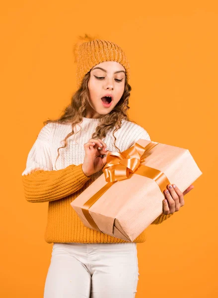 Teen girl received holiday gift. Best christmas gifts. Child excited unpacking gift. Kid little girl hold gift box with ribbon on yellow background. Christmas present for daughter. Enjoy surprises.