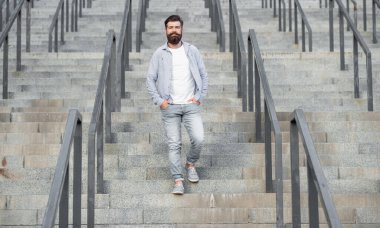 Sakallı adam aşağı iniyor. Uzun boylu, sakallı bir adam. Merdivenlerdeki hippi çocuk..