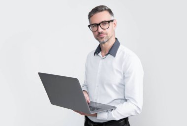 Gri arka planda bilgisayar üzerinde çalışan gözlüklü olgun bir çalışan..