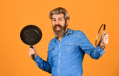 Mutfak gereçleri. Mutfak aletleri. İsimsiz dökme demir pişirme kabı. Tencerenin cam kapağı. Yapışkan olmayan kaplamalı politetrafluoretilen teflon. Adam yeni marka tavayı tutuyor. Sağlıklı yemek pişirmek..