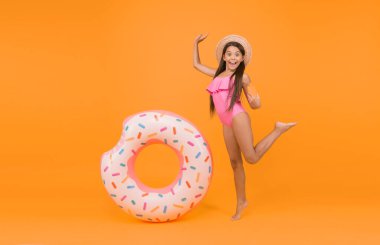 Eğlenceli bir aksesuar. Yaz tatili aktivitesi. Mayo ve hasır şapkalı neşeli küçük kız. Havuz ve kumsal eğlencesi. çocukluk mutluluğu. Çocuk güneşten korunuyor. Küçük güzellik. Lastik halkalı mutlu çocuk..