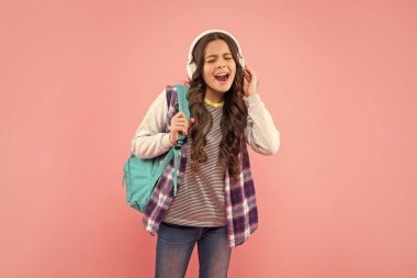 Online eğitim. Okula dönüyorum. Kulaklıklı mutlu kız. Müzik dinle. Kablosuz kulaklık cihazı aksesuarı. Yeni teknoloji. Çocukluk gelişimi. Sırt çantalı, modern kulaklıklı çocuk..