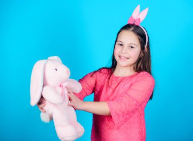 Mutlu çocukluk. Tavşan kulakları aksesuar. Güzel oynak bunny çocuk yumuşak oyuncak sarılmak. Tavşan kız şirin oyuncak üzerinde mavi arka plan ile. Çocuk gülümseyen oyun bunny oyuncak. Paskalya kutsadı. Paskalya ruhu içinde elde.