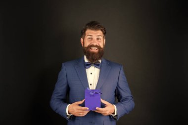 Smokinli, papyon takan, siyah arka planda, ödül kutulu mutlu bir adam. özel selamlama.