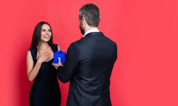 love couple with present isolated on red, copy space. love couple with present at studio. love couple with present on background. photo of love couple with present box.