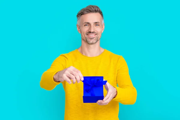 smiling man shopper with present on background. photo of man shopper with present. man shopper with present isolated on blue. man shopper with present in studio.