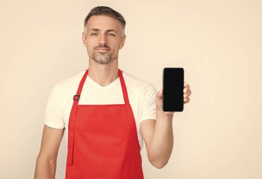 Önlüklü gülümseyen olgun bir adam akıllı telefona fotokopi alanı sunuyor..