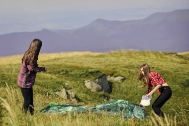 Kamp becerileri konsepti. Hiçliğin ortasında. Kızlar dağın tepesine çadır kurdular. Kamp ve yürüyüş. Yaz maceraları. Geçici konutlar. Kamp gezisi. Çadır kuracak bir ortağın olması ne güzel..
