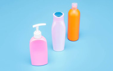 Çoklu renkli HDPE kozmetik ürünleri kapaklı paketleme kapsülleri ve pompa dağıtıcı mavi arkaplan kopyalama alanı, şişeler.