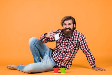 Mutlu, sakallı, sakalsız, şık saçlı, sıradan kıyafetler giyen, kahve içen, enerjik bir adam..