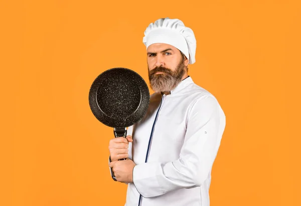 Nonstick cookware. Frying without oil. Professional kitchenware. Bearded chef preparing breakfast. Nonstick pan for frying. Enameled cooking vessels. Man hold pan. Frying meal. Healthy food.