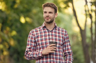 Damalı gömlekli, kahve fincanı olan pozitif bir genç..