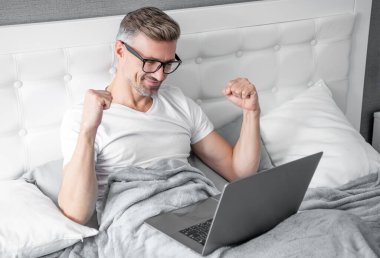 Gözlüklü olgun bir adamın laptopla yatakta çalışmasına sevindim..