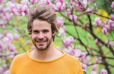 Bahar sezonu. Botanik ve doğa. Mutlu bahar konsepti. Hippi çiçek aromasının tadını çıkarır. Tıraşsız bir adam manolya çiçeği koklar. İlkbahar konsepti. Erkek çiçekli arka plan çözüldü. Bahar güzeli.