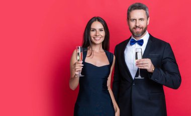 couple cheering and celebrate isolated on red, copy space. couple cheering and celebrate in studio. couple cheering and celebrate on background. photo of couple cheering and celebrate with champagne.